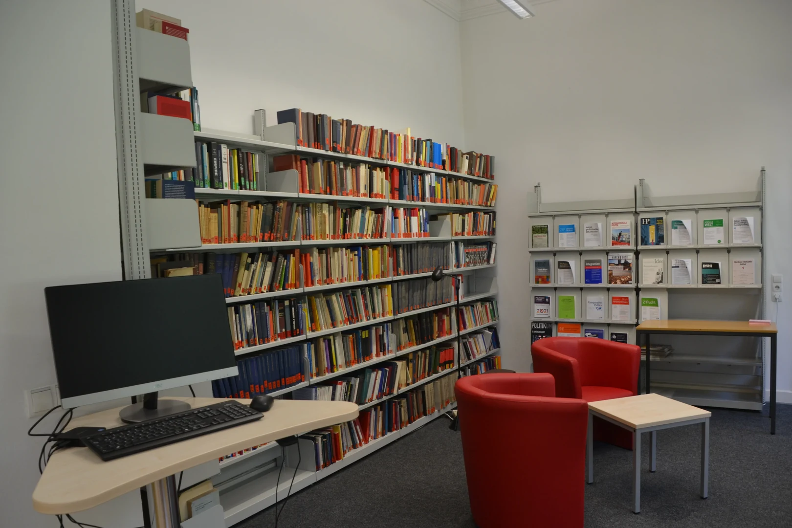 Eine Wissenschaftlerin und ein Wissenschaftler arbeiten hinter einer Glasfassade und mischen Chemikalien mit Großgeräten.